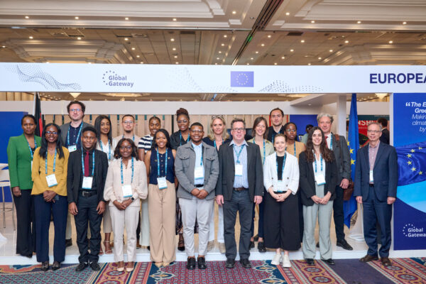 A group of professionals and partners from GET.transform and other organisations stand together for a group photo in front of the European Union pavilion at the summit.